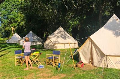 Cuisine extérieure en bambou avec plan de travail, tabouret, réfrigérateur, ustensiles et vaisselle dans un cadre naturel.