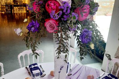 Jeune femme portant une couronne de fleurs blanches, vêtue de dentelle blanche, dans un jardin verdoyant.