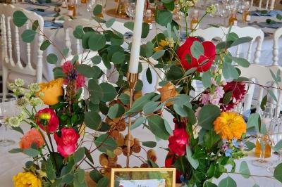 Jeune femme portant une couronne de fleurs blanches, vêtue de dentelle blanche, dans un jardin verdoyant.