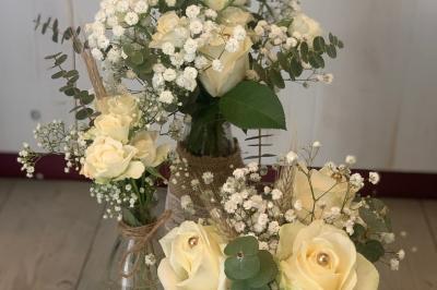 Jeune femme portant une couronne de fleurs blanches, vêtue de dentelle blanche, dans un jardin verdoyant.