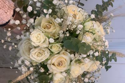 Jeune femme portant une couronne de fleurs blanches, vêtue de dentelle blanche, dans un jardin verdoyant.
