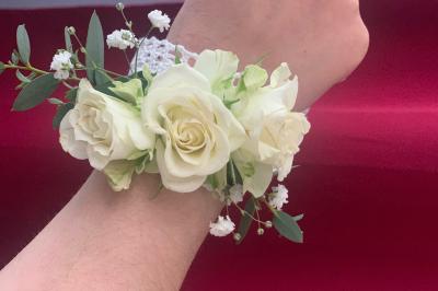 Jeune femme portant une couronne de fleurs blanches, vêtue de dentelle blanche, dans un jardin verdoyant.