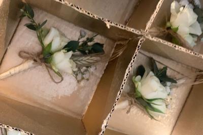 Jeune femme portant une couronne de fleurs blanches, vêtue de dentelle blanche, dans un jardin verdoyant.