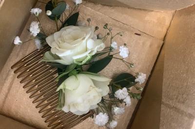 Jeune femme portant une couronne de fleurs blanches, vêtue de dentelle blanche, dans un jardin verdoyant.