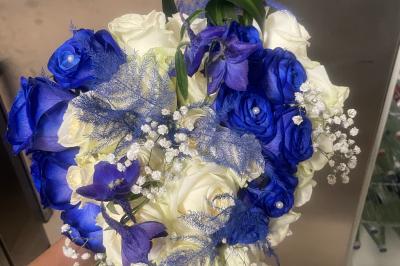 Jeune femme portant une couronne de fleurs blanches, vêtue de dentelle blanche, dans un jardin verdoyant.