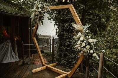 Jeune femme portant une couronne de fleurs blanches, vêtue de dentelle blanche, dans un jardin verdoyant.