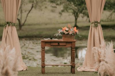 Jeune femme portant une couronne de fleurs blanches, vêtue de dentelle blanche, dans un jardin verdoyant.