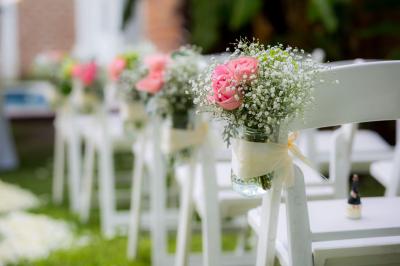 Jeune femme portant une couronne de fleurs blanches, vêtue de dentelle blanche, dans un jardin verdoyant.