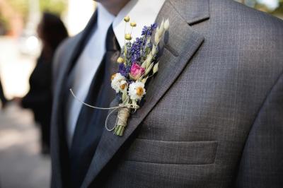 Jeune femme portant une couronne de fleurs blanches, vêtue de dentelle blanche, dans un jardin verdoyant.