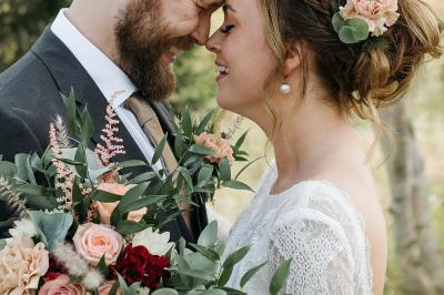 Jeune femme portant une couronne de fleurs blanches, vêtue de dentelle blanche, dans un jardin verdoyant.
