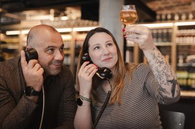 Un homme et une femme regardent une boîte dans un magasin de vins avec des étagères remplies de bouteilles en arrière-plan.