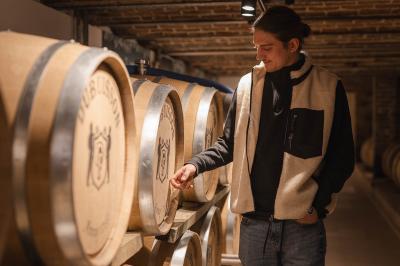 Un homme et une femme regardent une boîte dans un magasin de vins avec des étagères remplies de bouteilles en arrière-plan.