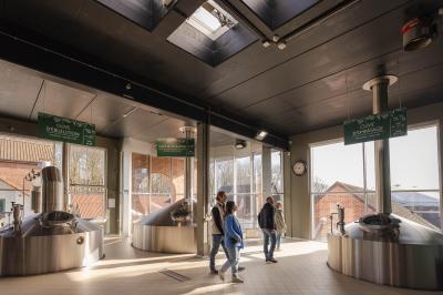 Un homme et une femme regardent une boîte dans un magasin de vins avec des étagères remplies de bouteilles en arrière-plan.