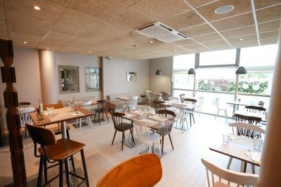 Salle de bain avec baignoire-douche, lavabo, miroir éclairé, toilettes et carrelage au sol.