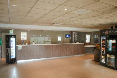 Salle de bain avec baignoire-douche, lavabo, miroir éclairé, toilettes et carrelage au sol.