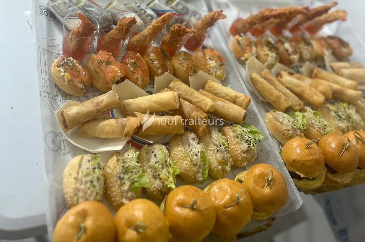 Plateaux garnis de bouchées variées : mini-burgers, rouleaux de printemps, sushis et beignets de crevettes.