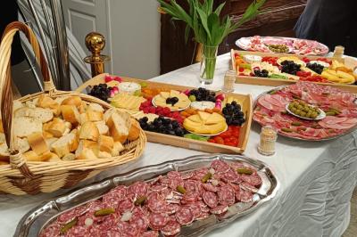 Buffet avec assortiments de sandwichs, samoussas, mini-burgers, canapés et coupes de fruits sur une table blanche.