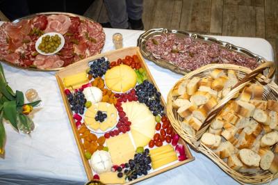 Buffet avec assortiments de sandwichs, samoussas, mini-burgers, canapés et coupes de fruits sur une table blanche.