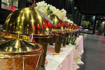 Buffet avec assortiments de sandwichs, samoussas, mini-burgers, canapés et coupes de fruits sur une table blanche.