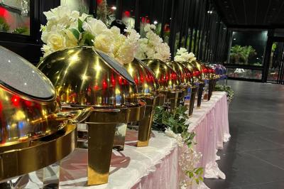 Buffet avec assortiments de sandwichs, samoussas, mini-burgers, canapés et coupes de fruits sur une table blanche.