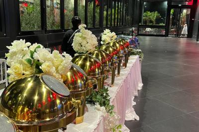 Buffet avec assortiments de sandwichs, samoussas, mini-burgers, canapés et coupes de fruits sur une table blanche.