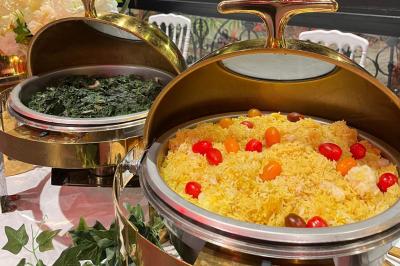 Buffet avec assortiments de sandwichs, samoussas, mini-burgers, canapés et coupes de fruits sur une table blanche.