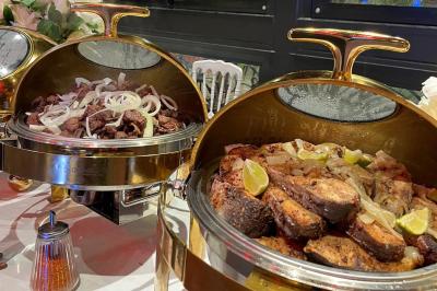 Buffet avec assortiments de sandwichs, samoussas, mini-burgers, canapés et coupes de fruits sur une table blanche.