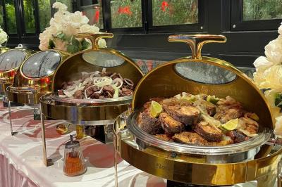 Buffet avec assortiments de sandwichs, samoussas, mini-burgers, canapés et coupes de fruits sur une table blanche.