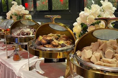 Buffet avec assortiments de sandwichs, samoussas, mini-burgers, canapés et coupes de fruits sur une table blanche.