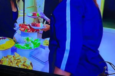 Buffet avec assortiments de sandwichs, samoussas, mini-burgers, canapés et coupes de fruits sur une table blanche.