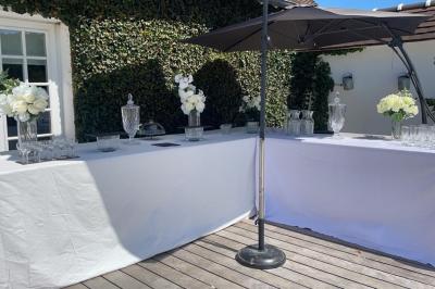 Buffet avec assortiments de sandwichs, samoussas, mini-burgers, canapés et coupes de fruits sur une table blanche.