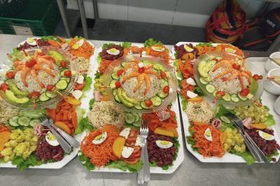 Plateaux garnis de crudités variées, riz, légumes frais, œufs durs et garnitures colorées disposés sur une table.