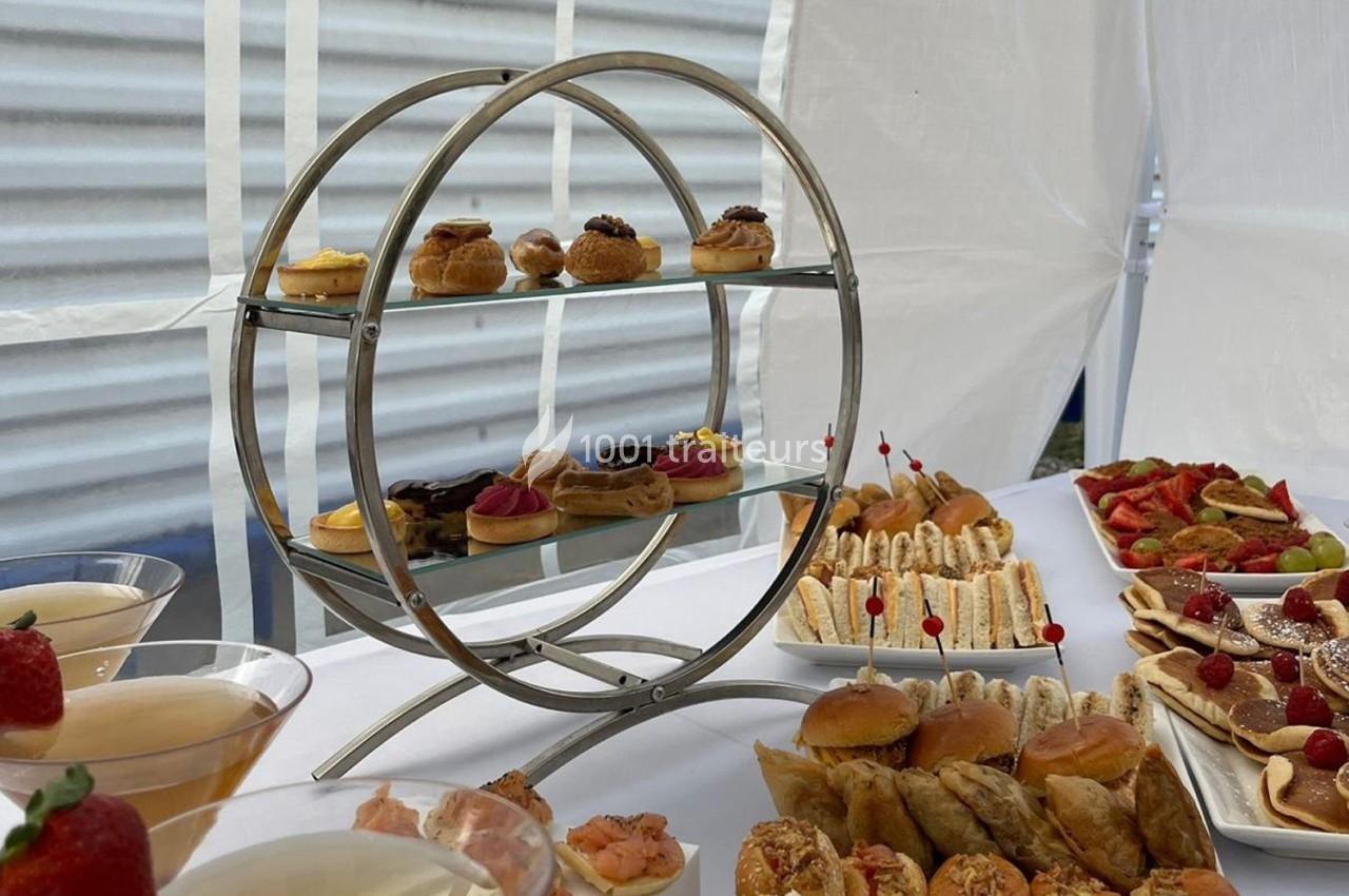 Plateau circulaire avec des pâtisseries miniatures, entouré de divers amuse-bouches et desserts sur une table.