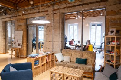 Quatre personnes discutent autour d'une table dans une salle de réunion lumineuse avec un ordinateur au centre.