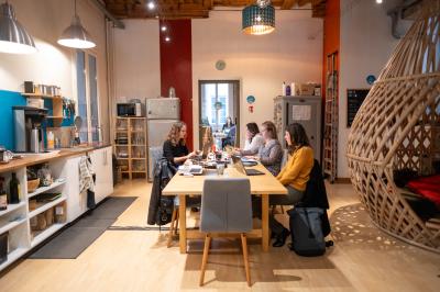 Quatre personnes discutent autour d'une table dans une salle de réunion lumineuse avec un ordinateur au centre.