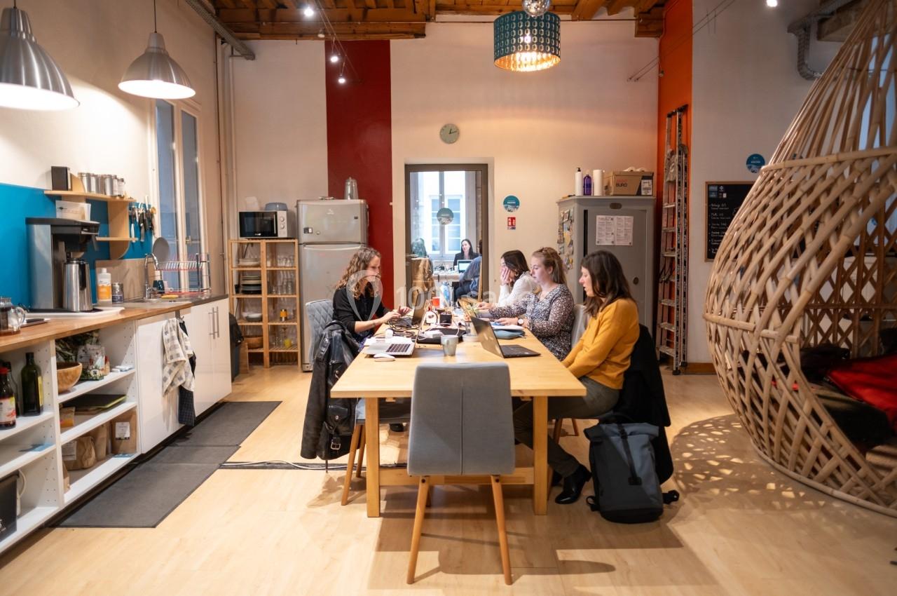 Personnes travaillant sur des ordinateurs portables dans un espace de coworking lumineux avec une ambiance décontractée.