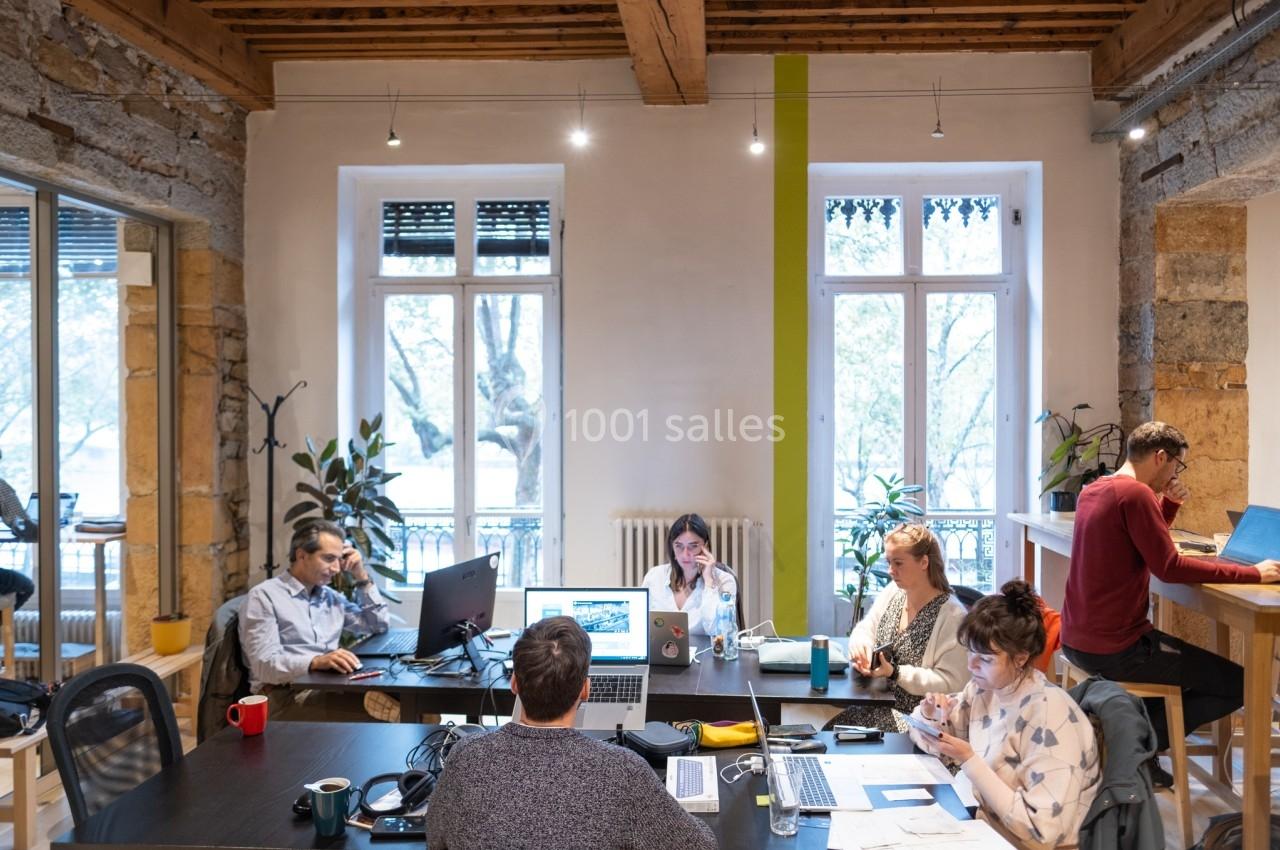 Personnes travaillant sur des ordinateurs portables dans un espace de coworking lumineux avec des plantes et des grandes…