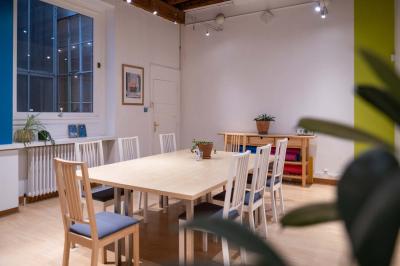 Quatre personnes discutent autour d'une table dans une salle de réunion lumineuse avec un ordinateur au centre.