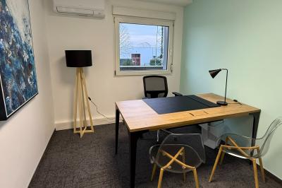 Salle de réception avec tables rondes dressées, nappes blanches, serviettes rouges et chaises grises sur parquet clair.