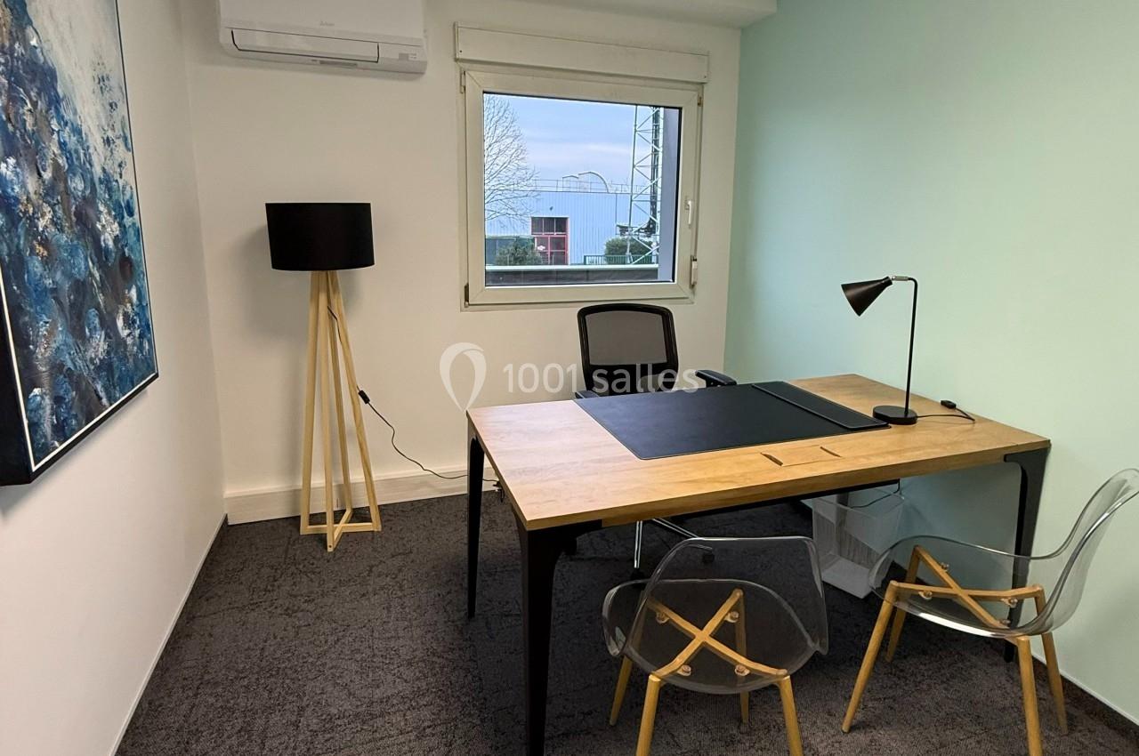 Bureau lumineux avec un grand bureau en bois, deux chaises transparentes, une lampe noire et une fenêtre donnant sur l…