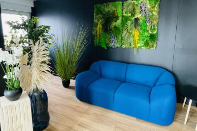 Salle de réception avec tables rondes dressées, nappes blanches, serviettes rouges et chaises grises sur parquet clair.