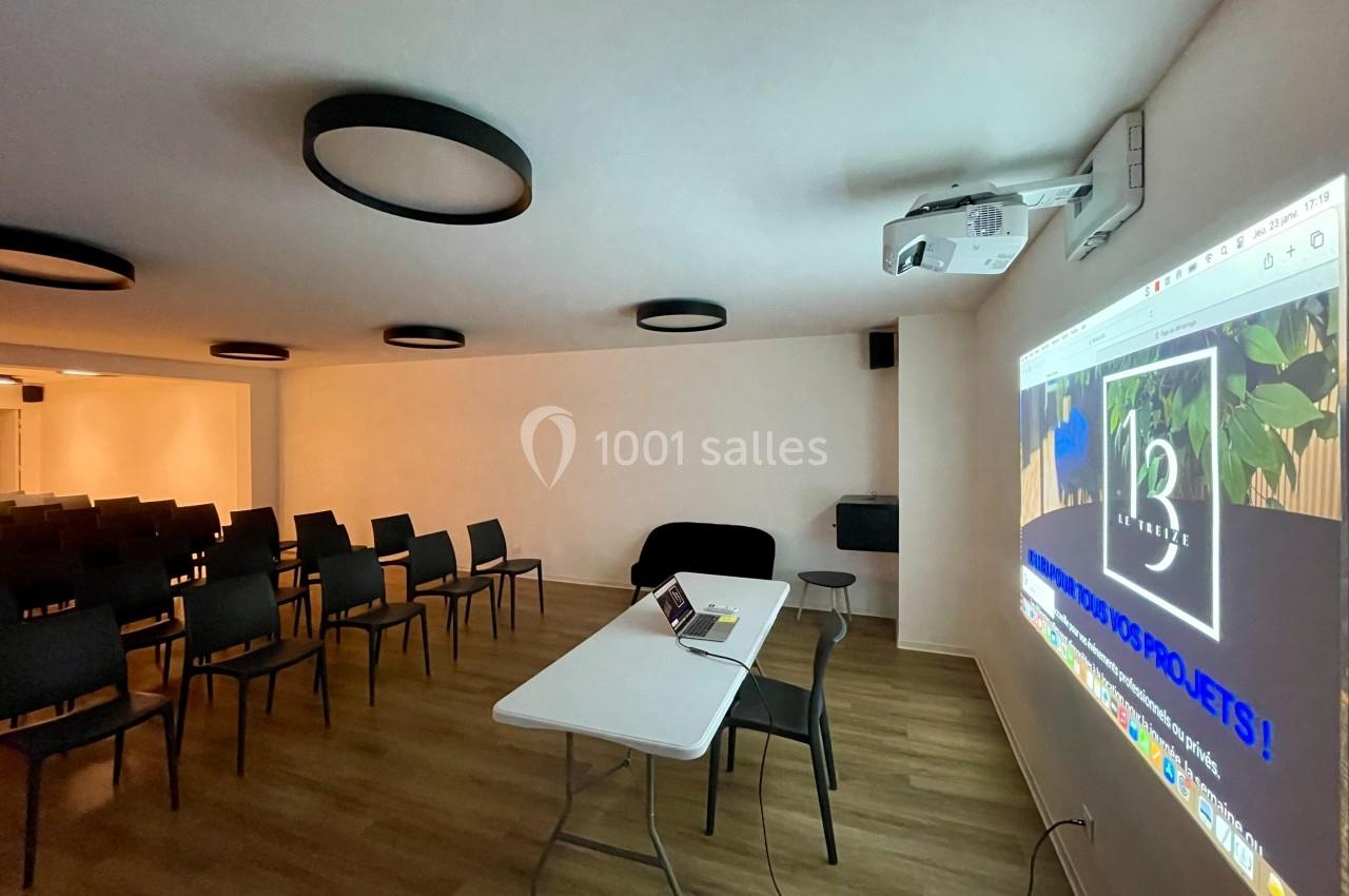 Salle de réunion équipée de chaises, d'une table avec un ordinateur portable et d'un projecteur affichant une présentation.