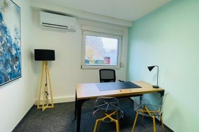 Salle de réception avec tables rondes dressées, nappes blanches, serviettes rouges et chaises grises sur parquet clair.