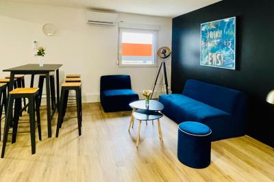 Salle de réception avec tables rondes dressées, nappes blanches, serviettes rouges et chaises grises sur parquet clair.