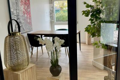 Salle de réception avec tables rondes dressées, nappes blanches, serviettes rouges et chaises grises sur parquet clair.