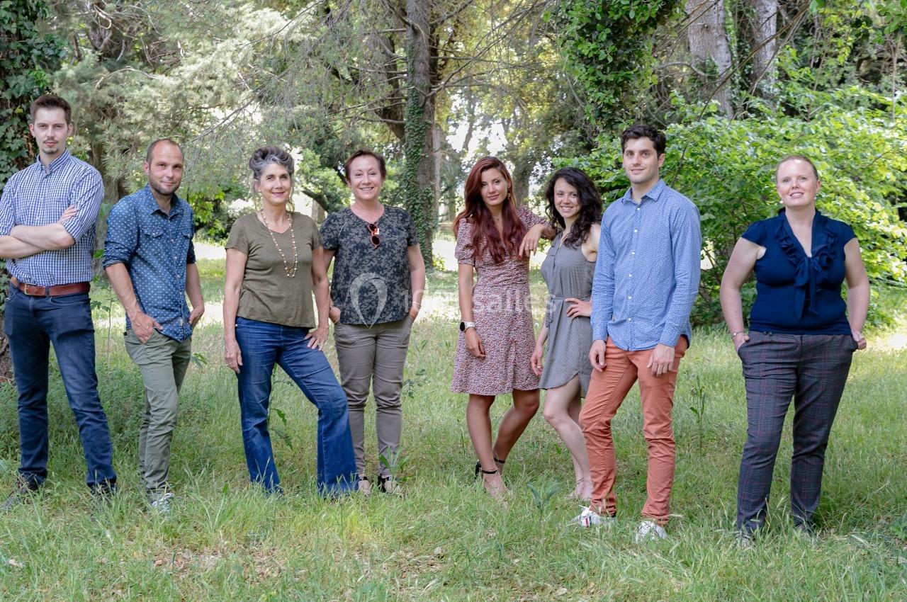 Un groupe de huit personnes posant debout dans un espace extérieur verdoyant.