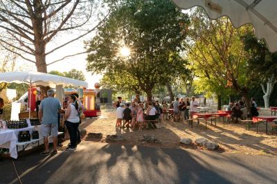 Paysage au crépuscule avec silhouettes de collines, arbres et habitations sous un ciel dégradé du bleu à l'orange.