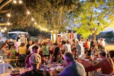 Paysage au crépuscule avec silhouettes de collines, arbres et habitations sous un ciel dégradé du bleu à l'orange.