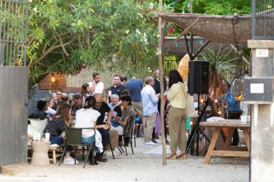 Paysage au crépuscule avec silhouettes de collines, arbres et habitations sous un ciel dégradé du bleu à l'orange.