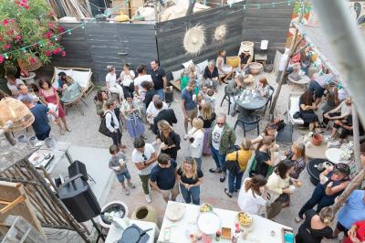 Paysage au crépuscule avec silhouettes de collines, arbres et habitations sous un ciel dégradé du bleu à l'orange.